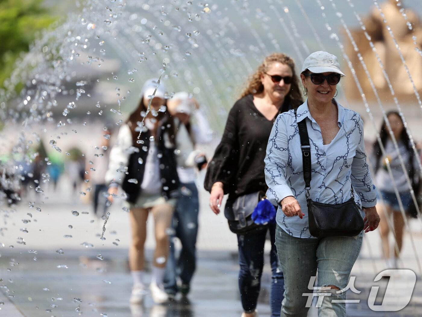본문 이미지 - 대체로 맑고 포근한 '초여름 날씨'를 보인 12일 오후 서울 광화문광장 분수터널에서 외국인 관광객들이 더위를 식히고 있다. 2025.5.12/뉴스1 ⓒ News1 황기선 기자
