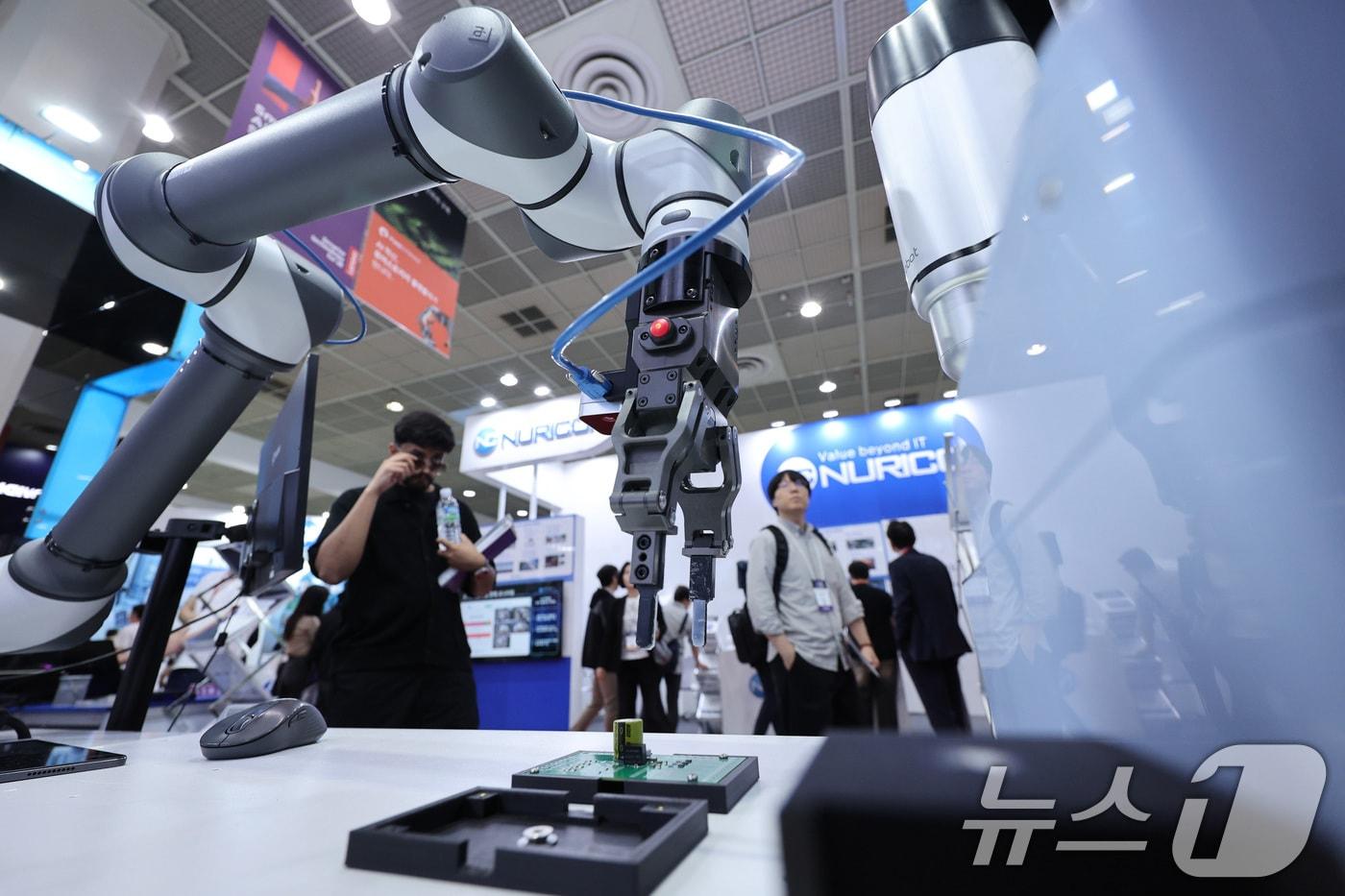 14일 서울 강남구 코엑스에서 열린 국제인공지능대전에서 관람객들이 인공지능(AI)을 활용한 로봇팔을 살펴보고 있다. 2025.5.14/뉴스1 ⓒ News1 신웅수 기자