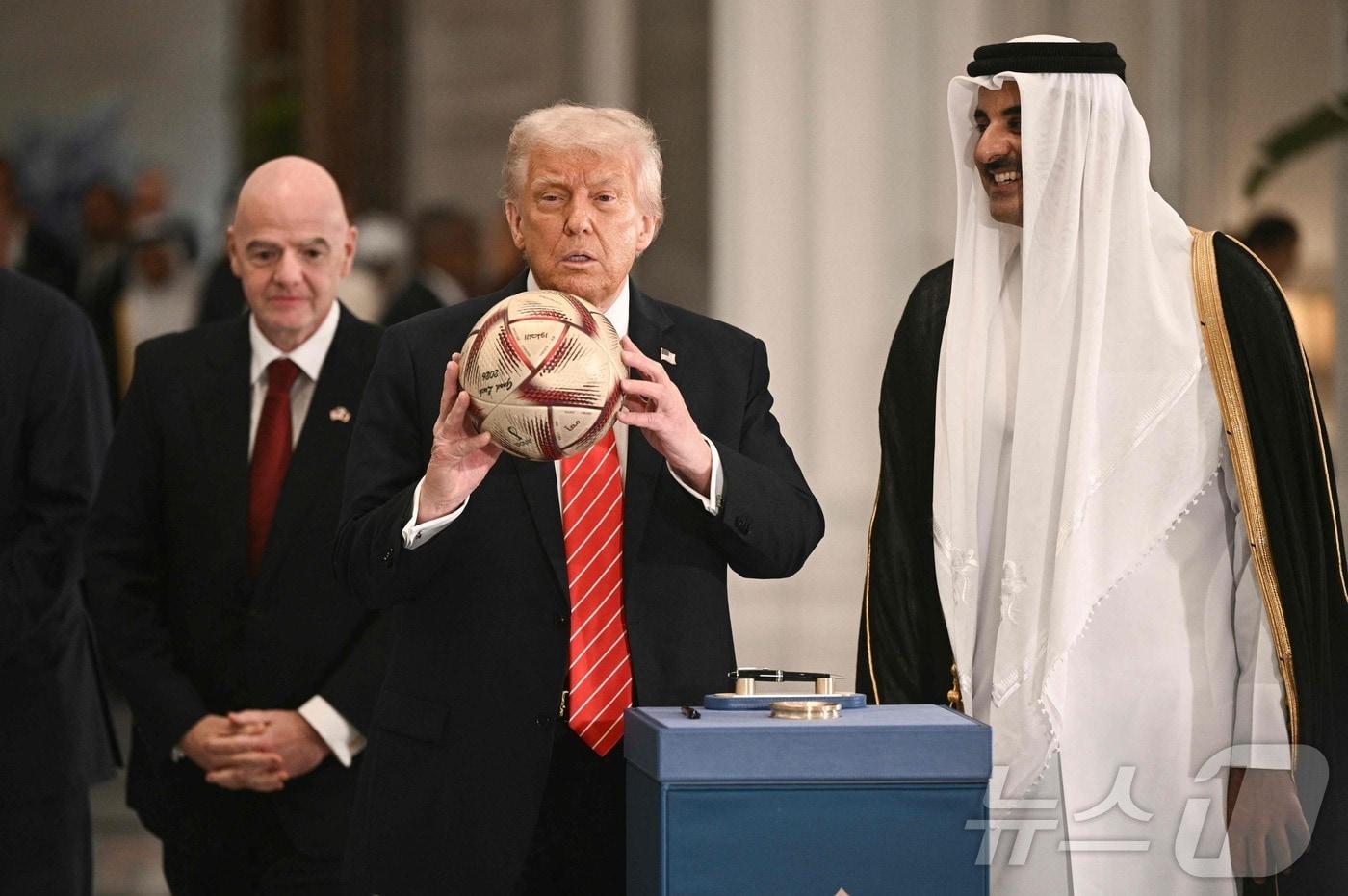 도널드 트럼프 미국 대통령이 14일(현지시간) 도하 루사일 궁전에서 셰이크 타밈 빈 하마드 알사니 카타르 국왕, 잔니 인판티노 FIFA 회장과 사인한 월드컵 축구 공을 들고 있다. 2025.05.15 ⓒ AFP=뉴스1 ⓒ News1 우동명 기자