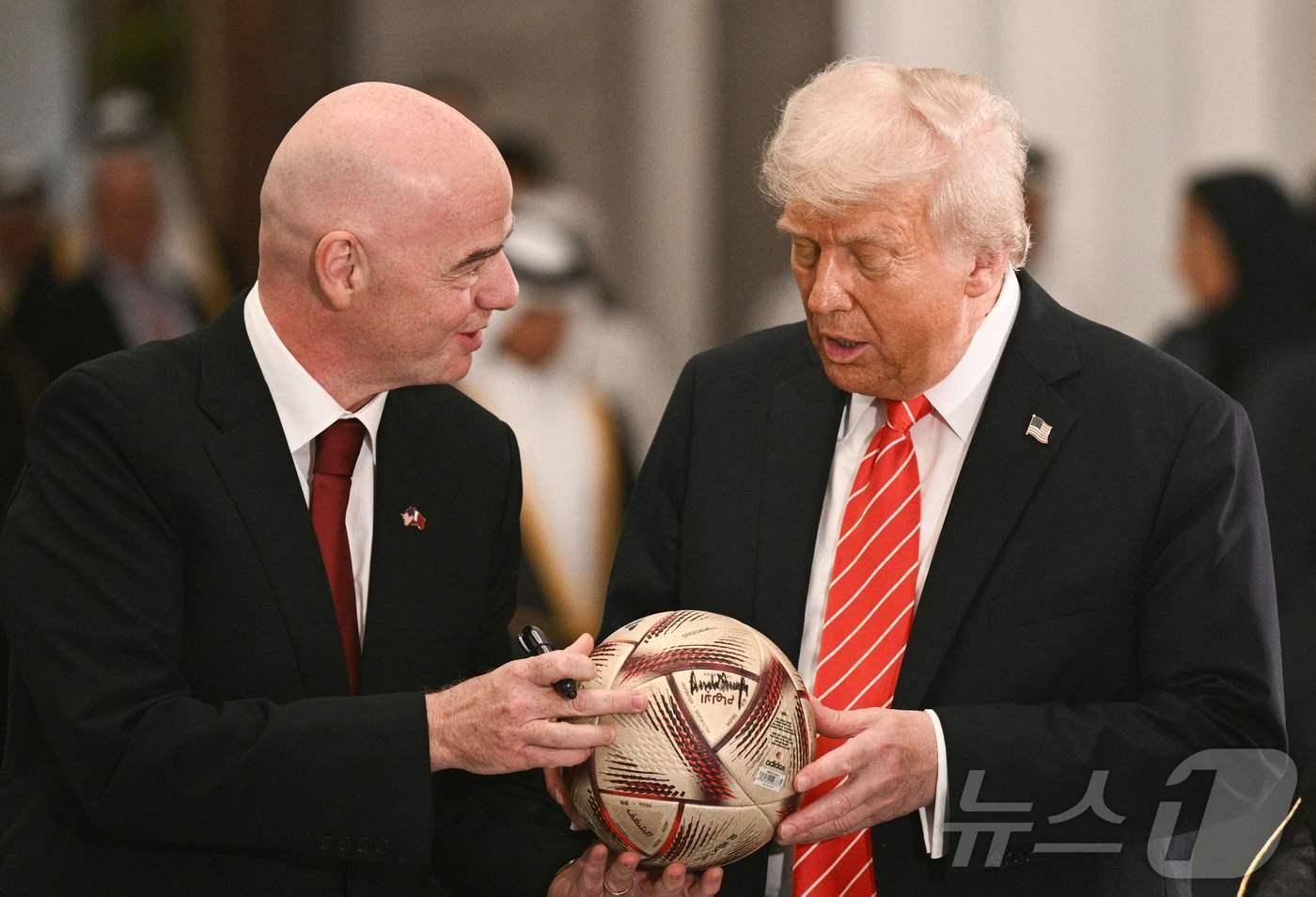 본문 이미지 - 도널드 트럼프 미국 대통령이 14일(현지시간) 카타르 도하 루사일 궁전에서 잔니 인판티노 FIFA 회장한테 서명한 축구 공을 받고 있다. 2025.05.15 ⓒ AFP=뉴스1