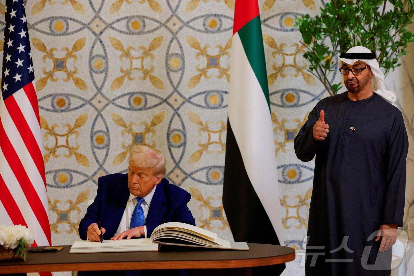 도널드 트럼프 미국 대통령이 지난 5월 15일&#40;현지시간&#41; 아부다비의 대통령 궁에서 방명록에 서명을 하는 동안 셰이크 무함마드 빈 자이드 알 나흐얀 UAE 대통령이 엄지를 치켜 세우고 있다. 2025.05.16 ⓒ 로이터=뉴스1 ⓒ News1 우동명 기자