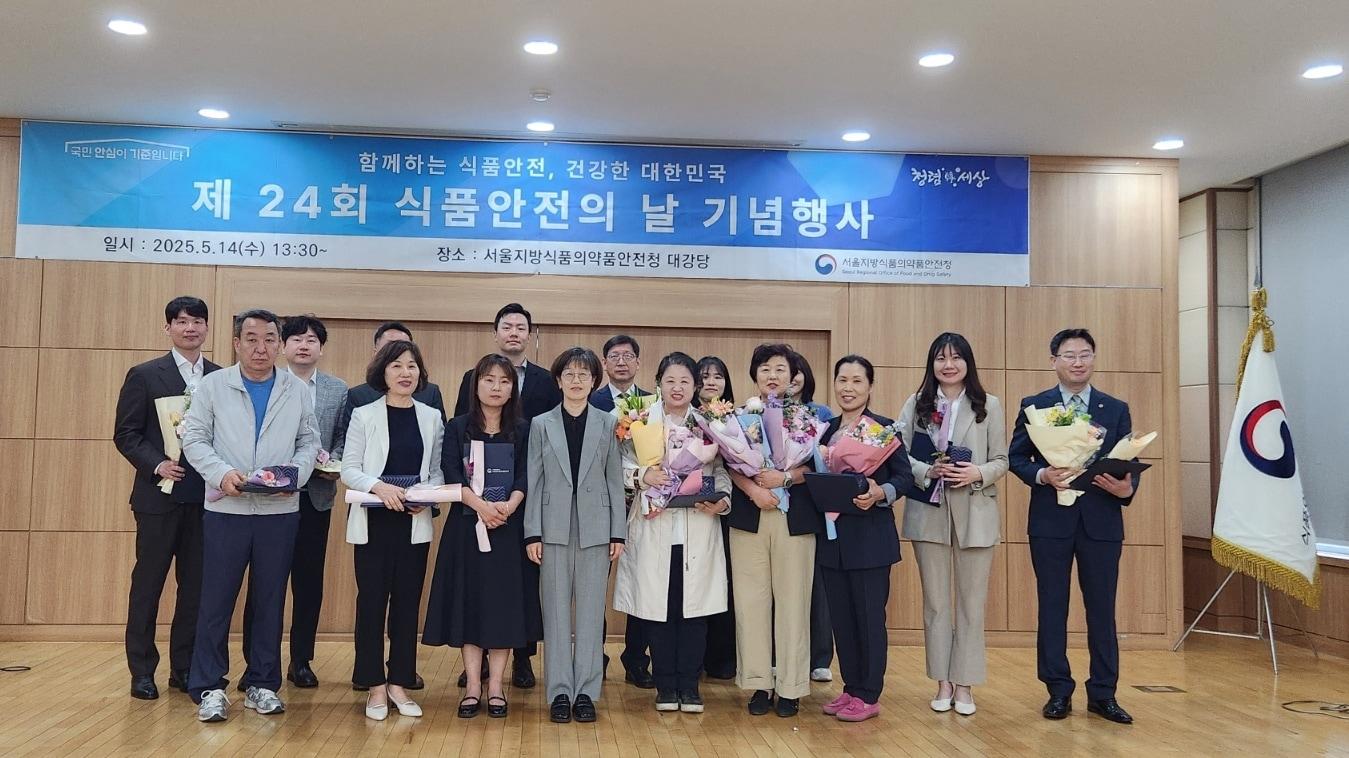 본문 이미지 - 2025년 5월 14일 서울지방식품의약품안전청 대강당에서 열린 ‘제24회 식품안전의 날 기념행사’에서 수상자들과 함께 기념촬영 중인 칠갑농산 파주공장 이영미 대표(앞줄 가운데 흰 트렌치코트 소지, 꽃다발 수상자) / 사진=칠갑농산 제공