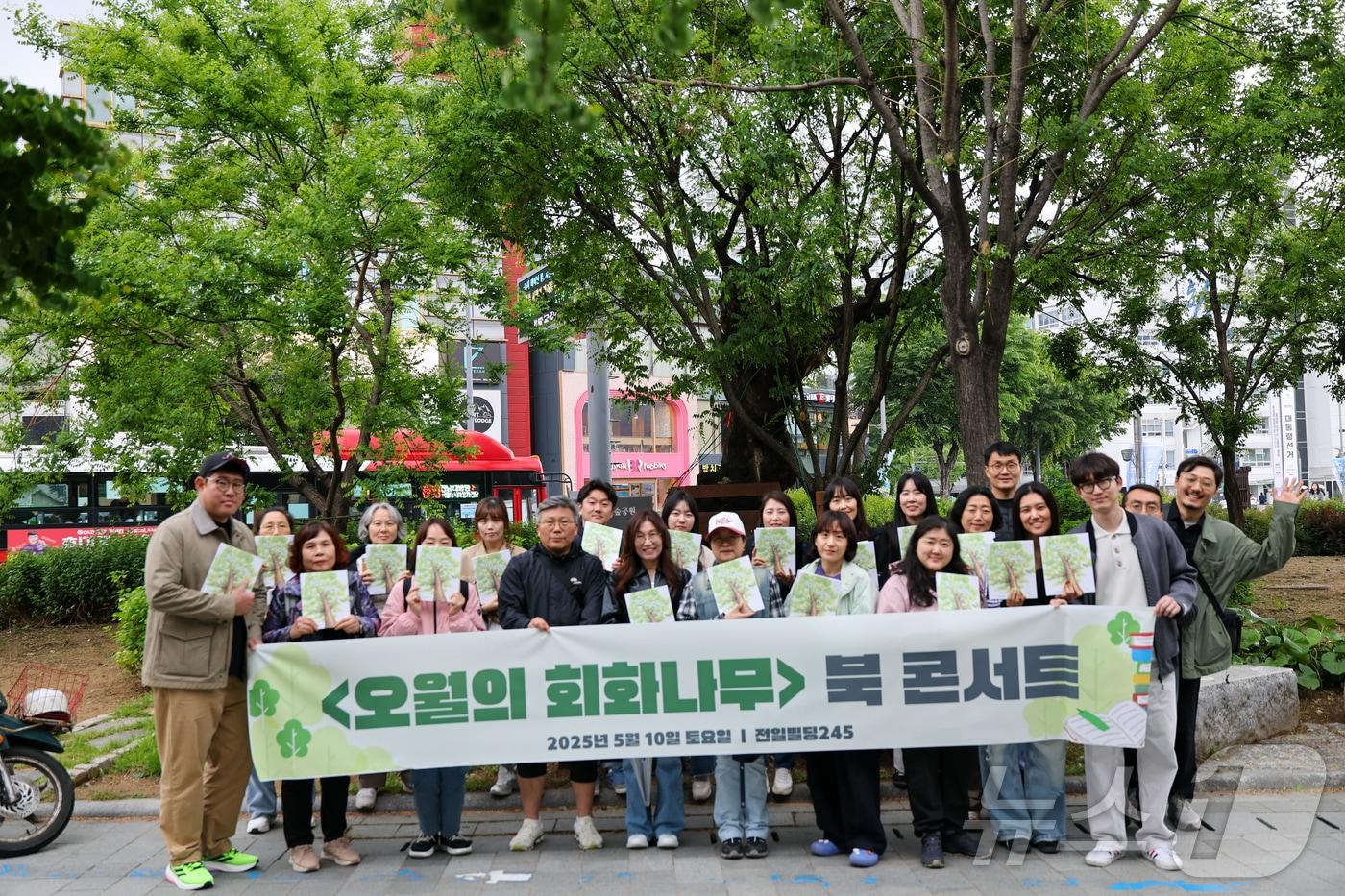 5·18민주화운동을 상징하는 ‘오월의 회화나무’ 앞에서 책을 들고 사진을 찍는 시민들.&#40;광주실천교육교사모임 제공. 재배포 및 DB 금지&#41;