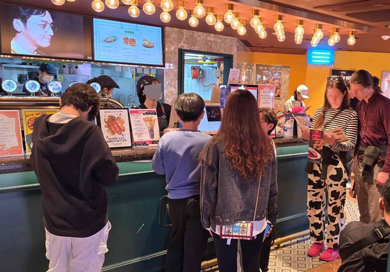 본문 이미지 - 롯데월드 어드벤처 매직아일랜드에서 운영중인 BBQ 매장에서 BBQ 치킨을 주문하기 위해 손님들이 기다리고 있다.(BBQ 제공)