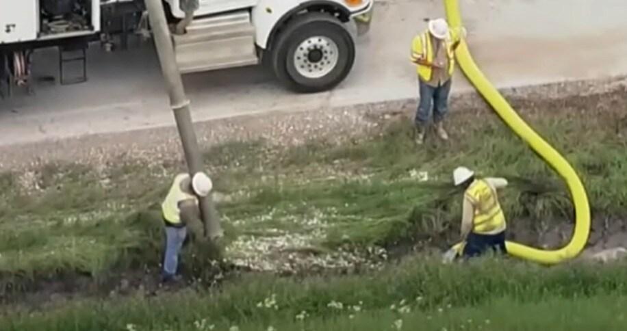 본문 이미지 - 작업자들이 미국 텍사스주 앨보드 인근 고속도로에서 바닥에 흩어진 동전을 산업용 진공청소기로 빨아들이고 있다. <출처=CBS뉴스 기사 갈무리>