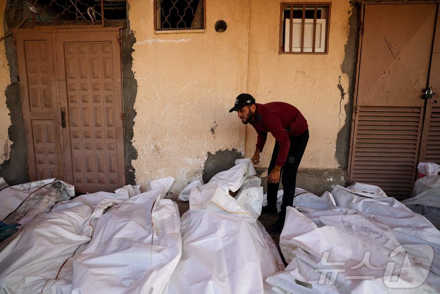 20일(현지시간) 가자지구 중부 데이르 엘발라에 있는 알아크사 순교자 병원에서 이스라엘의 공습으로 사망한 팔레스타인인들의 시신 사이에 한 남성이 서 있다. ⓒ AFP=뉴스1 ⓒ News1 권영미 기자