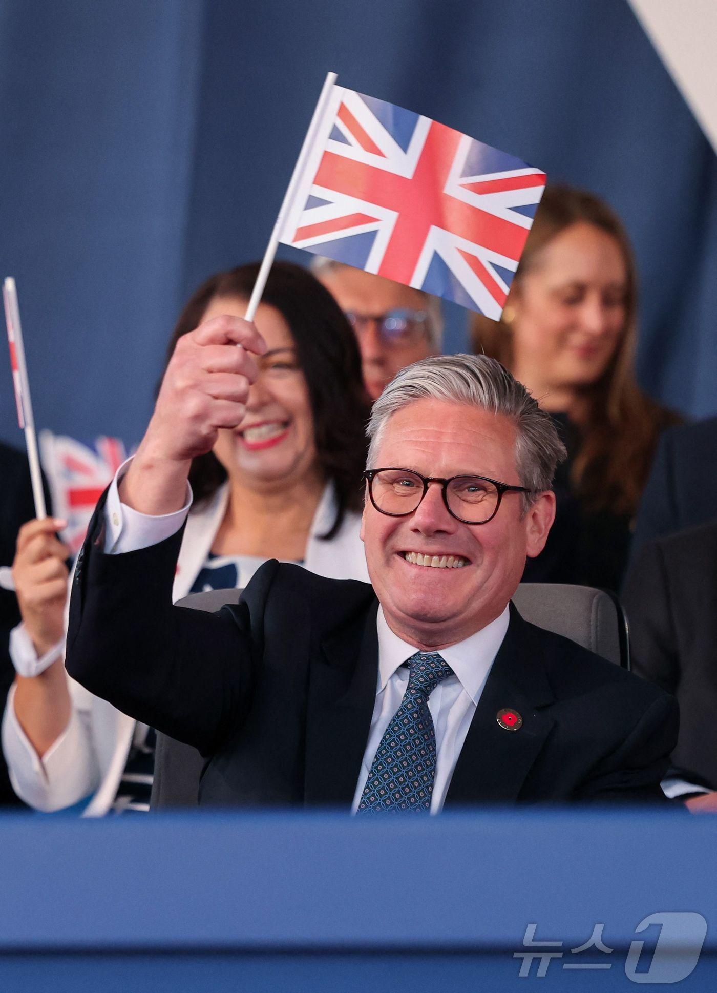 본문 이미지 - 키어 스타머 영국 총리가 8일&#40;현지시간&#41; 런던에서 열린 2차 세계대전 승전 기념 행사에 참석해 영국 국기를 흔들고 있다. 2025.05.08. ⓒ AFP=뉴스1 ⓒ News1 이지예 객원기자