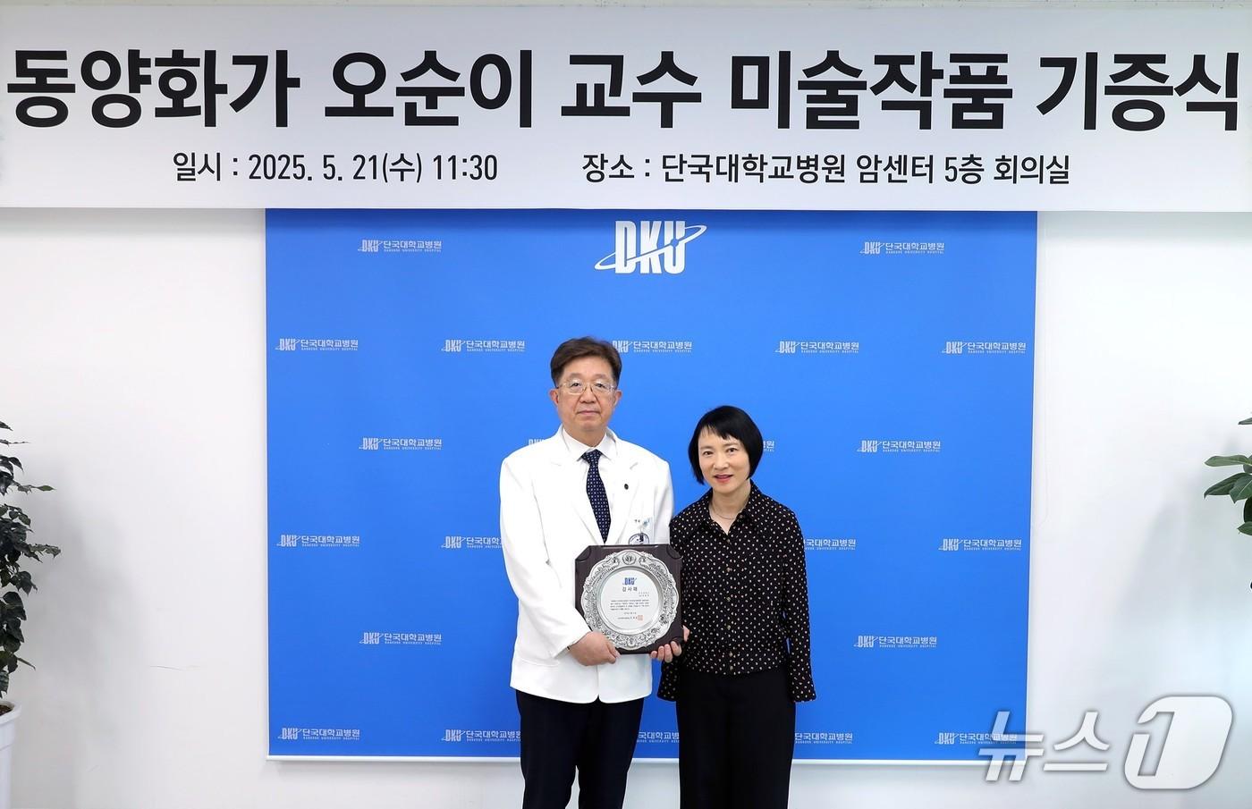 김재일 단국대병원장(왼쪽)이 작품을 기증한 오순이 단국대 교수에게 감사패를 전달한 뒤 기념 촬영을 하고 있다.(단국대 제공. 재판매 및 DB금지)