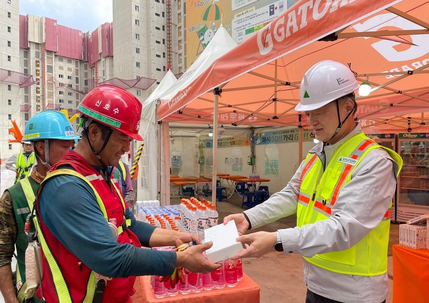 본문 이미지 - 현대건설 CSO 황준하 전무가 근로자에게 수분 보충과 탈수 예방을 위한 이온음료와 쿨링스프레이를 직접 전달하고, 근로자들의 노고를 격려하고 있다(현대건설 제공).