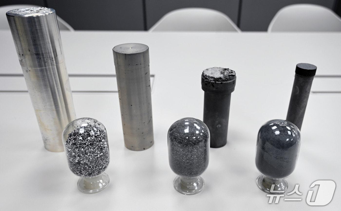 본문 이미지 - 연구팀이 개발한 소재 시편. 앞줄 원형 유리에 들어있는 시편 중 왼쪽에서 첫 번째는 기존의 방법으로 제조한 시편이다. 두 번째·세 번째는 연구팀이 새롭게 개발한 방법으로 제조한 시편으로, 기존보다 더 미세한(머리카락 절반 두께) 분말 형태를 나타내고 있다.(재료연 제공. 재판매 및 DB금지)