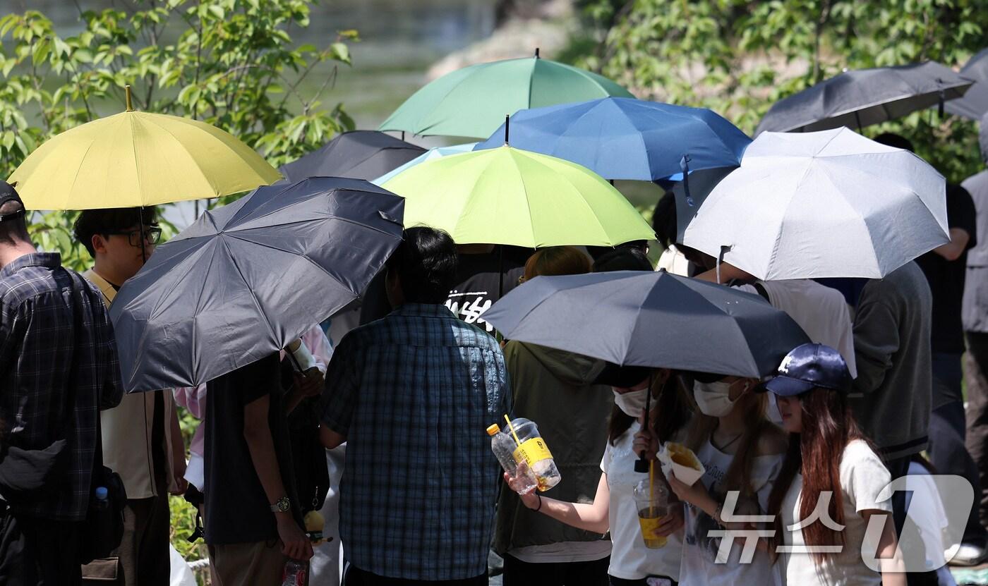 전국적으로 초여름 날씨를 보인 22일 서울 광진구 건국대학교에서 학생들이 우산과 양산으로 햇빛을 가린 채 노천극장 입장을 기다리고 있다. 2025.5.22/뉴스1 ⓒ News1 김성진 기자