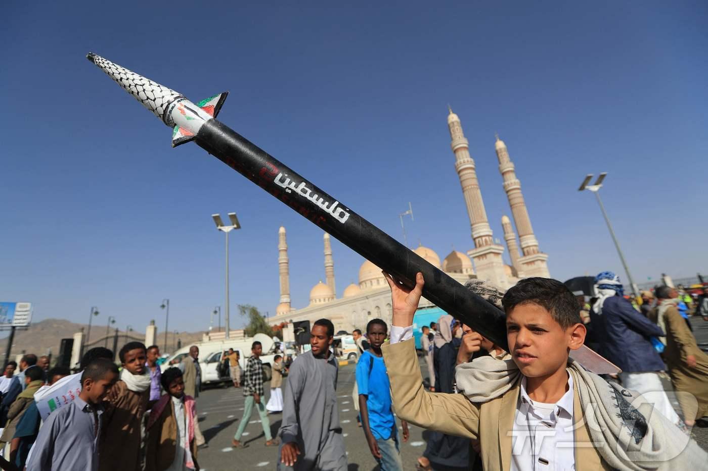 예멘의 한 소년이 가짜 미사일을 들고 팔레스타인과 가자지구와의 연대를 표명하는 시위에 참여하고 있다. 2025.05.16.ⓒ AFP=뉴스1