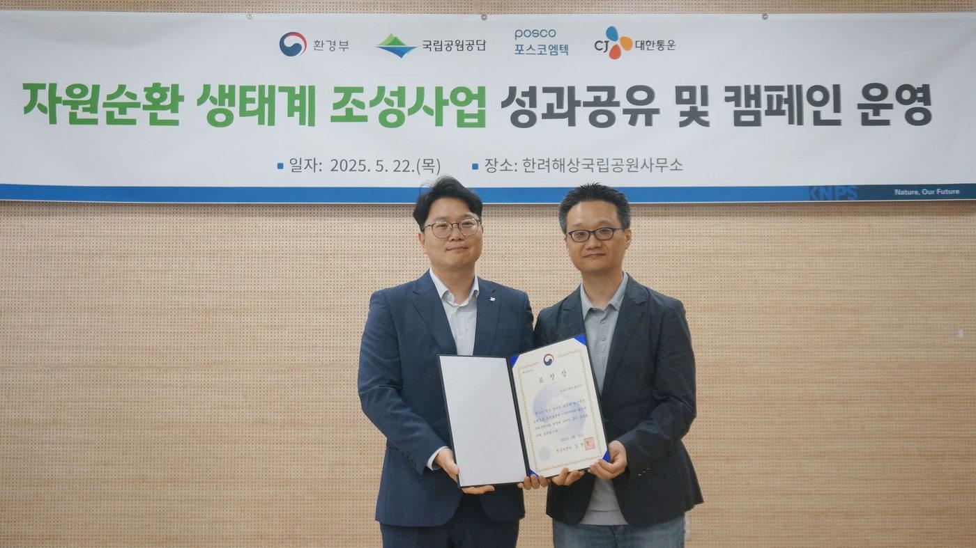 CJ대한통운이 자원순환활동 유공 시상식에서 환경부 장관 표창을 수상했다. CJ대한통운 이훈석 오네본부 경남사업담당(왼쪽)이 환경부 안중기 생활폐기물과 과장과 포즈를 취하고 있다. (CJ대한통운 제공)