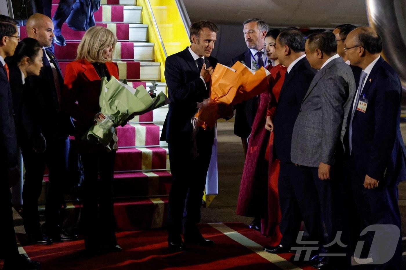 에마뉘엘 마크롱 프랑스 대통령&#40;가운데&#41;과 부인 브리지트 마크롱이 5월 25일 하노이 노이바이 국제공항에 도착해 베트남 관리들의 환영을 받고 있다. 2025.5.25 ⓒ AFP=뉴스1 ⓒ 