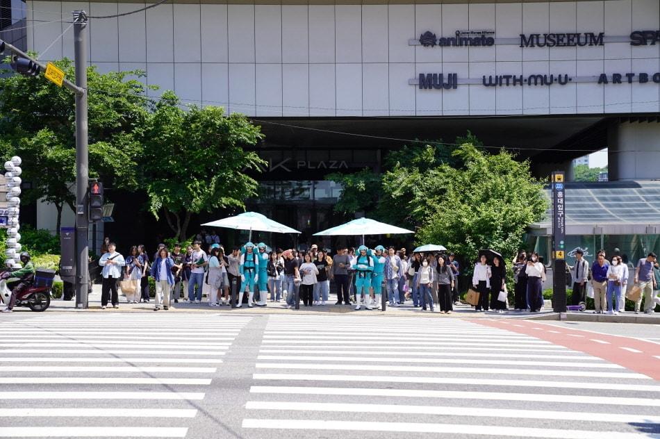 본문 이미지 - 횡단보도 앞에서 인간파라솔로 분장한 후레쉬맵 요원들이 시민들에게 그늘을 제공하는 이색 퍼포먼스로 시선을 끌었다.(삼양식품 제공)