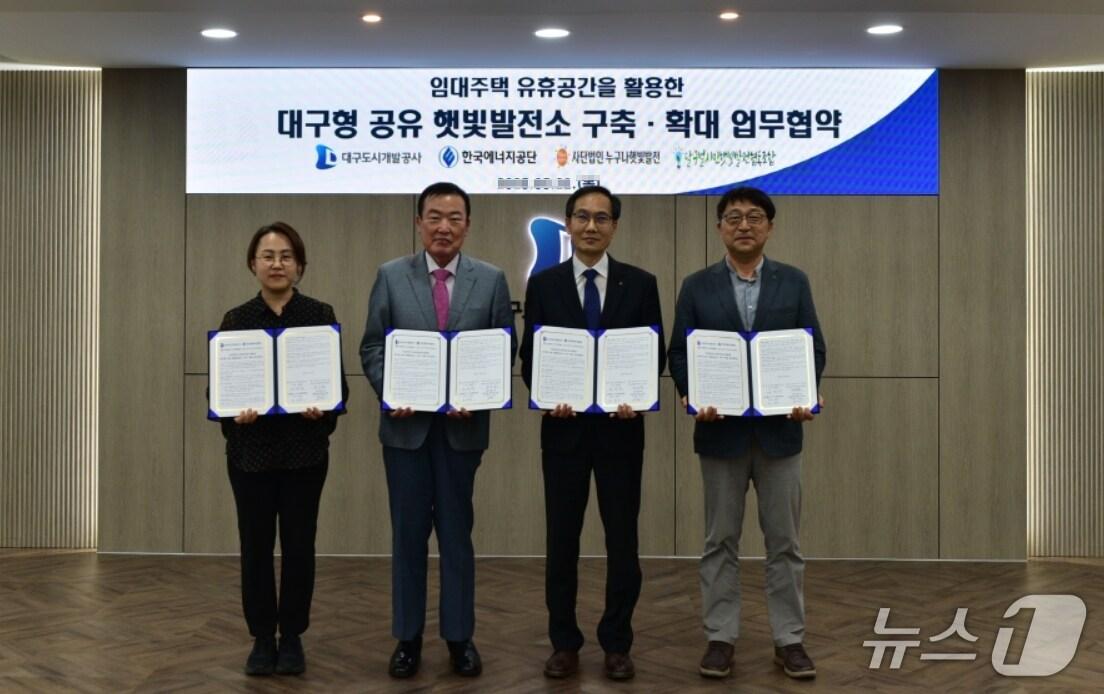 본문 이미지 - 정명섭 대구도시개발공사 사장&#40;왼쪽 두번째&#41;이 김은영 달구벌시민햇빛발전협동조합 이사장&#40;왼쪽&#41;, 정군모 한국에너지공단 대구경북본부장&#40;오른쪽 두번째&#41;, 정현수 &#40;사&#41;누구나햇빛발전 회장이 &#39;대구형공유햇빛발전소 구축 및 확대&#39;를 위한 업무협약을 체결한 뒤 협약서를 펼쳐 보이고 있다.&#40;대구도시개발공사 제공. 재판매 및 DB 금지&#41;
