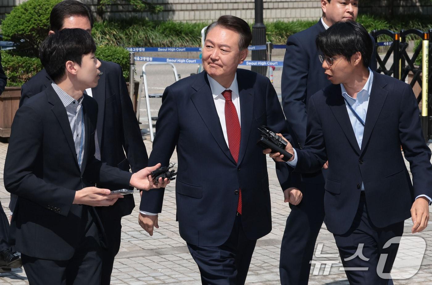 윤석열 전 대통령이 26일 서울 서초구 서울중앙지방법원에서 열린 내란 우두머리 혐의ㆍ직권남용 권리행사 방해 혐의 사건 5차 공판에 출석하며 지지자들을 바라보고 있다. 2025.5.26/뉴스1 ⓒ News1 사진공동취재단