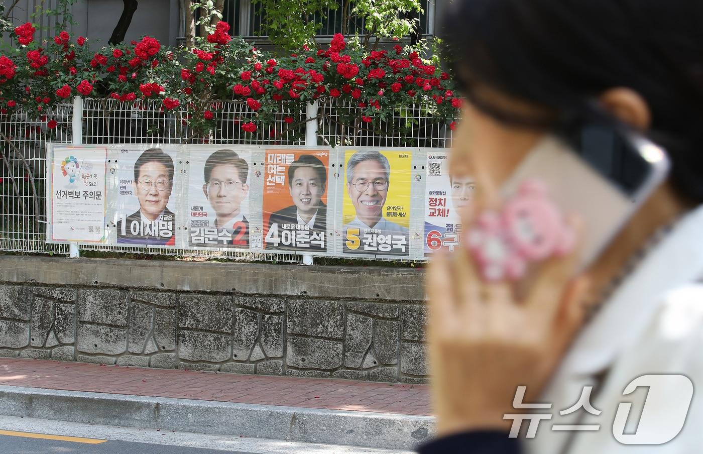 제21대 대통령선거 사전투표가 사흘 앞으로 다가온 26일 대구 중구 남산동 한 아파트 울타리 장미꽃 아래 붙은 후보자들의 선거 벽보 앞을 시민들이 지나고 있다. 이번 대통령선거 사전투표는 5월 29~30일 이틀간, 본투표는 6월 3일 하루 실시된다. 2025.5.26/뉴스1 ⓒ News1 공정식 기자