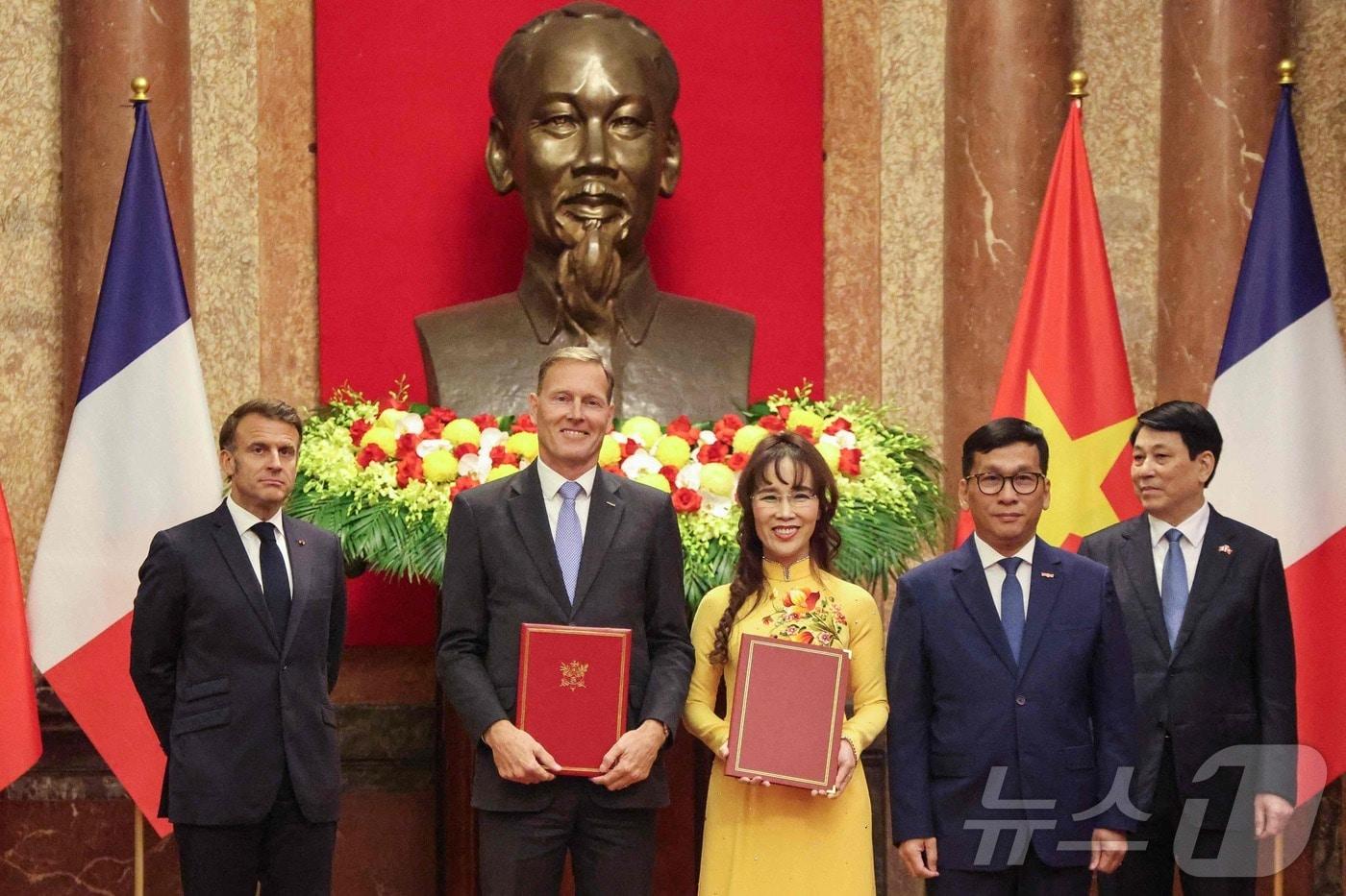 에마뉘엘 마크롱 프랑스 대통령&#40;좌&#41;, 르엉 끄엉 베트남 주석&#40;우&#41;, 바우터 반 베르쉬 에어버스 국제 총괄 부사장&#40;좌 두번째&#41;, 베트남 항공사인 비엣젯의 딘 비엣 푸엉 최고경영자&#40;우 두번째&#41;, 응웬 티 푸엉 타오 회장&#40;중앙&#41;이 26일 하노이 대통령궁에서 협약서를 교환하며 포즈를 취하고 있다. ⓒ AFP=뉴스1 ⓒ News1 신기림 기자