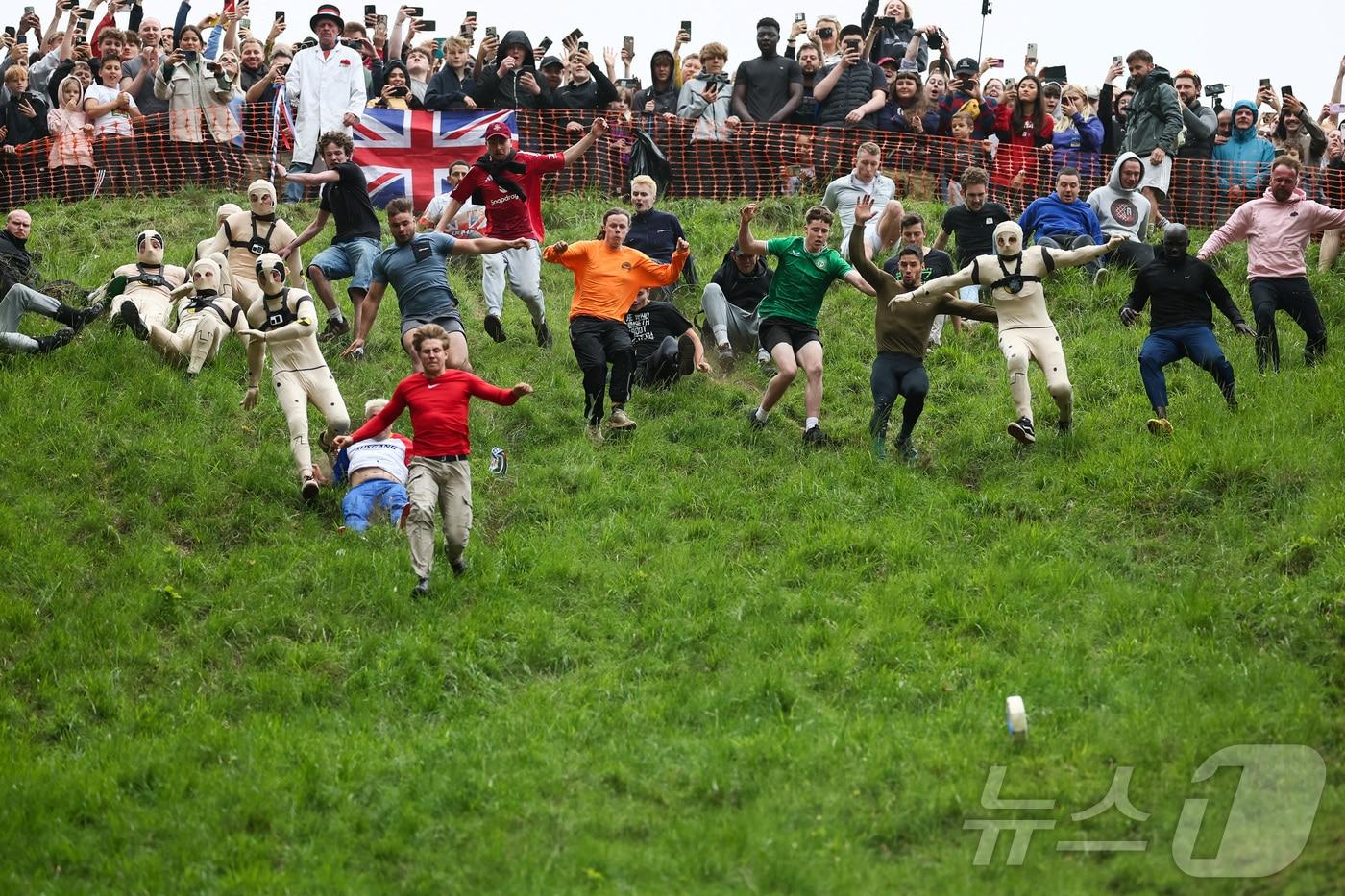 26일(현지시간) 영국 브록웍스의 쿠퍼스 힐에서 열린 '구르는 치즈 잡기' 대회에서 참가자들이 치즈를 쫒아 언덕을 내려가고 있다. ⓒ 로이터=뉴스1