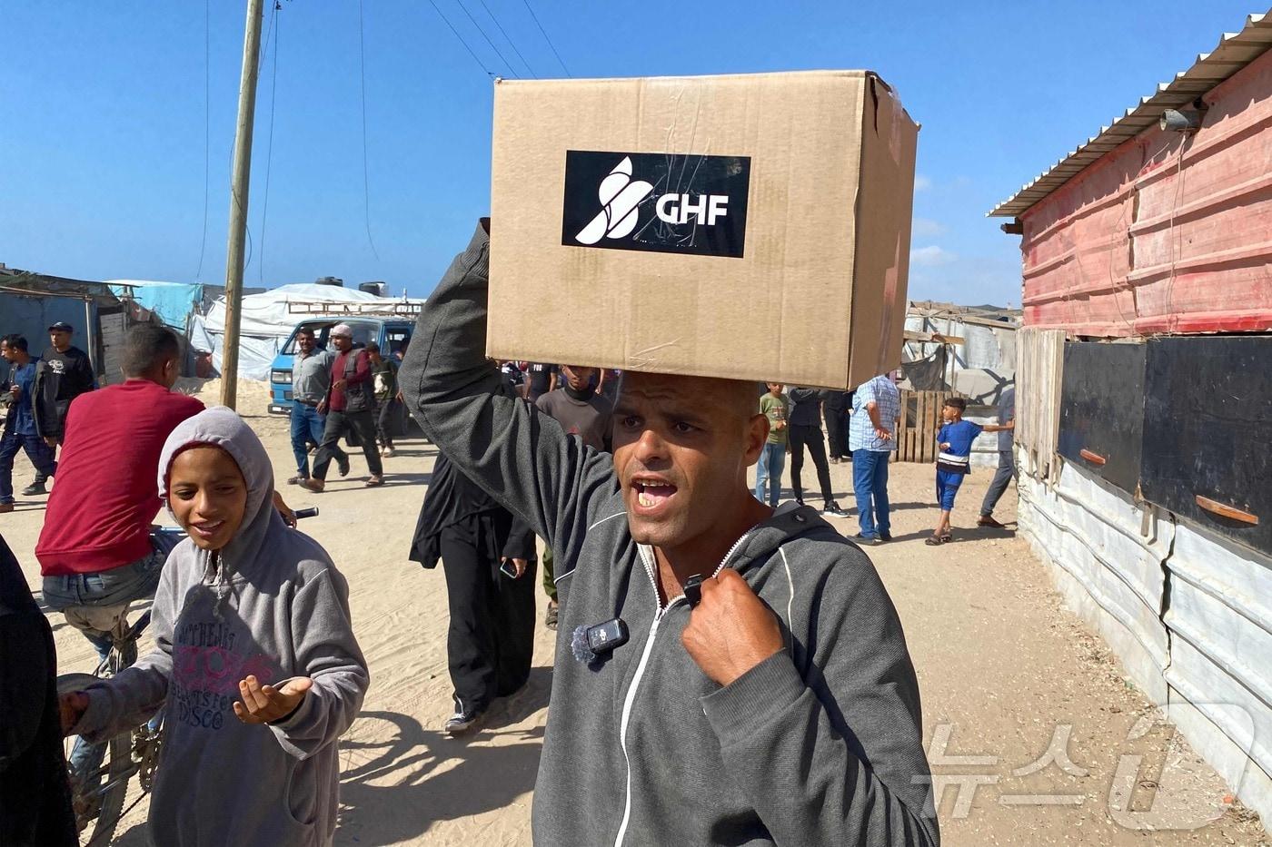 가자지구 남부에서 27일(현지시간) 가자인도주의재단(GHF)의 구호품 배급이 시작돼 주민들이 상자에 든 구호품을 받아가고 있다.2025.05.27.ⓒ AFP=뉴스1