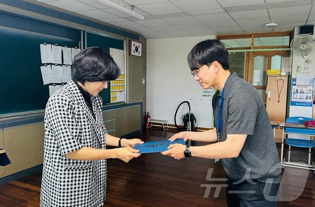 본문 이미지 - 백성동 전교조 광주지부 대변인(오른쪽)이 어려운 환경의 학생에 수여하는 장학증서를 교사에 대리전달하고 있다.(전교조 광주지부 제공. 재배포 및 DB 금지)