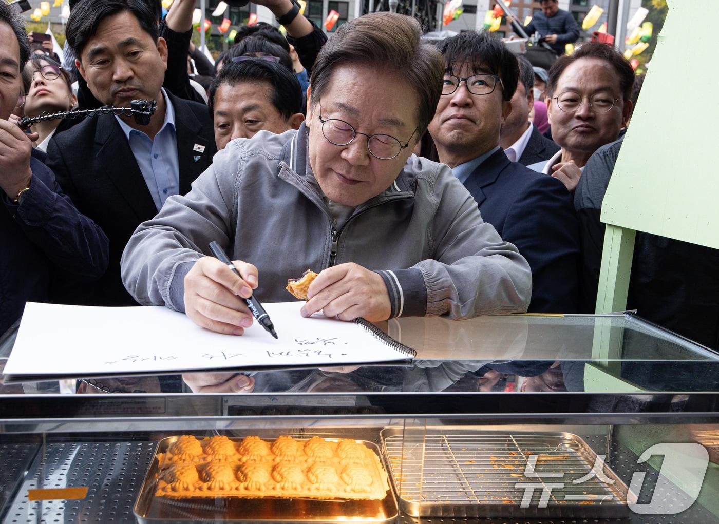 본문 이미지 - '골목골목 경청투어 : 동해안벨트편'에 나선 이재명 더불어민주당 대통령 후보가 3일 오후 강원 태백시 장성탄탄마당 일원에서 열린 2025년 태백 천상의 산나물 축제장에서 상인의 요청으로 메시지를 작성하고 있다. 2025.5.3/뉴스1 ⓒ News1 이재명 기자