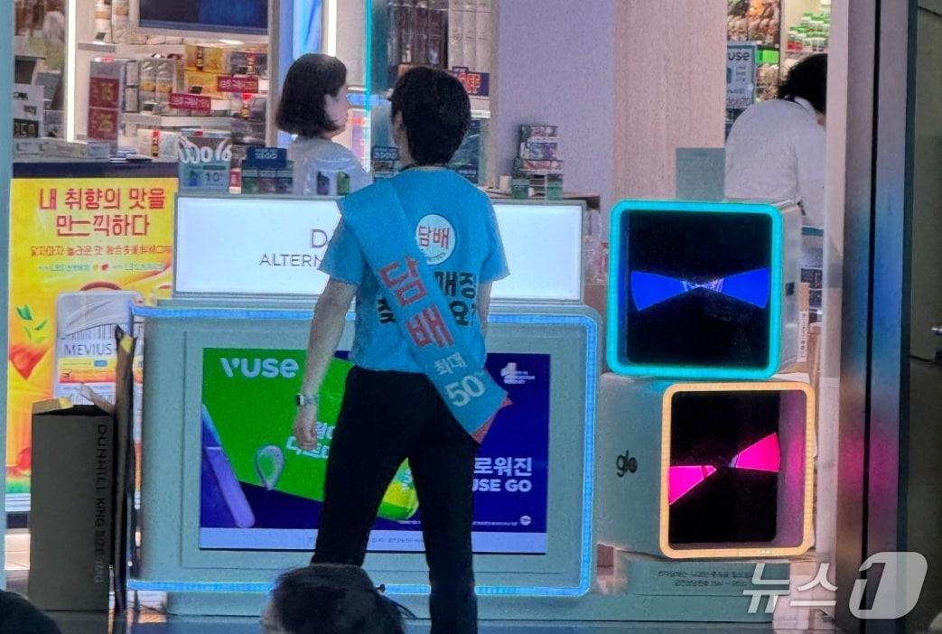 본문 이미지 - 인천국제공항의 한 면세점 직원이 담배 판매 홍보 문구가 인쇄된 티셔츠를 입고 돌아다니고 있다(독자 제공).