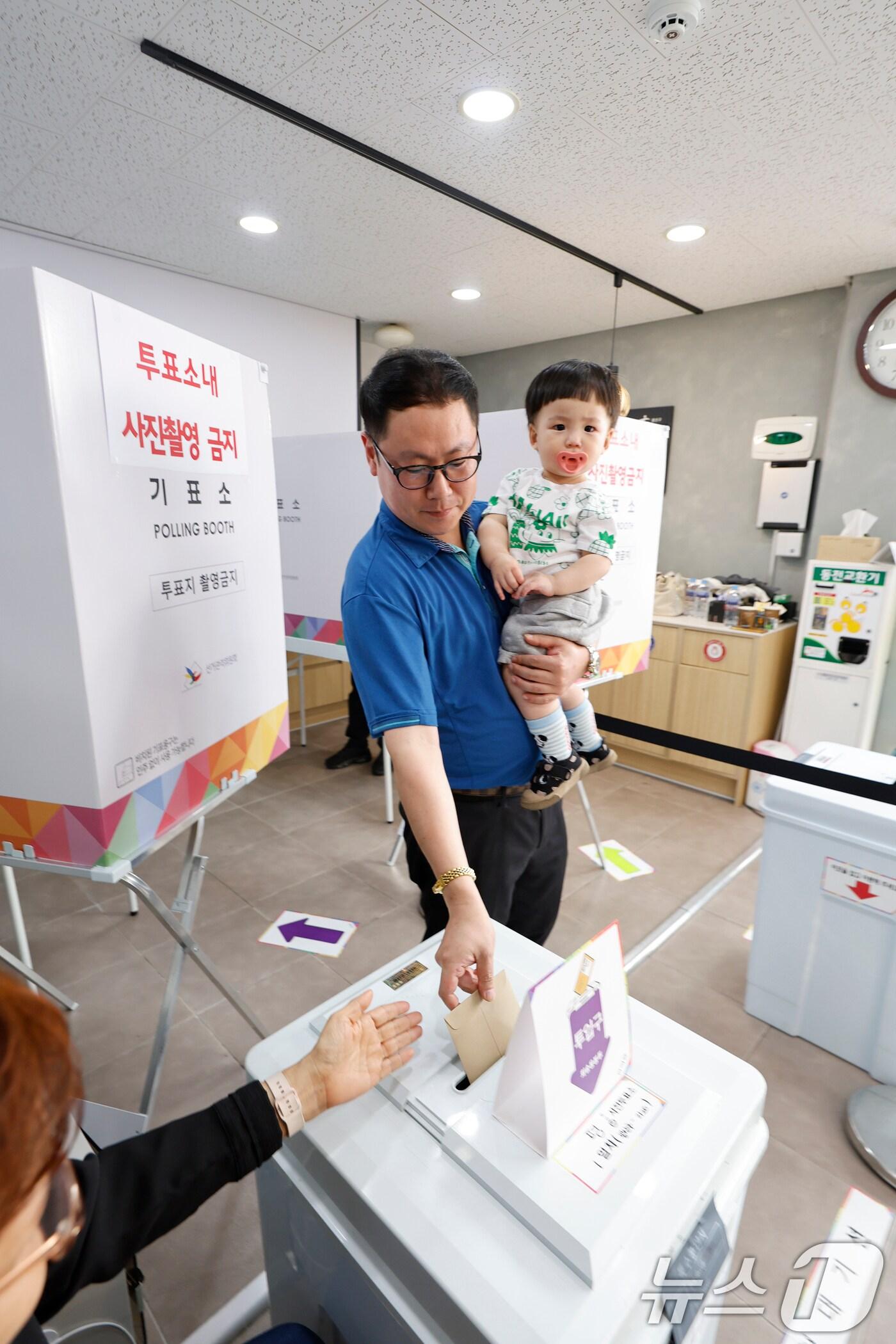 본문 이미지 - 제21대 대통령 선거 사전투표 둘째날인 30일 광주시 광산구 평동 드림센터 사전투표소에서 아빠를 따라온 아들이 함께 한 표를 행사하고 있다 2025.5.30/뉴스1 ⓒ News1 김태성 기자