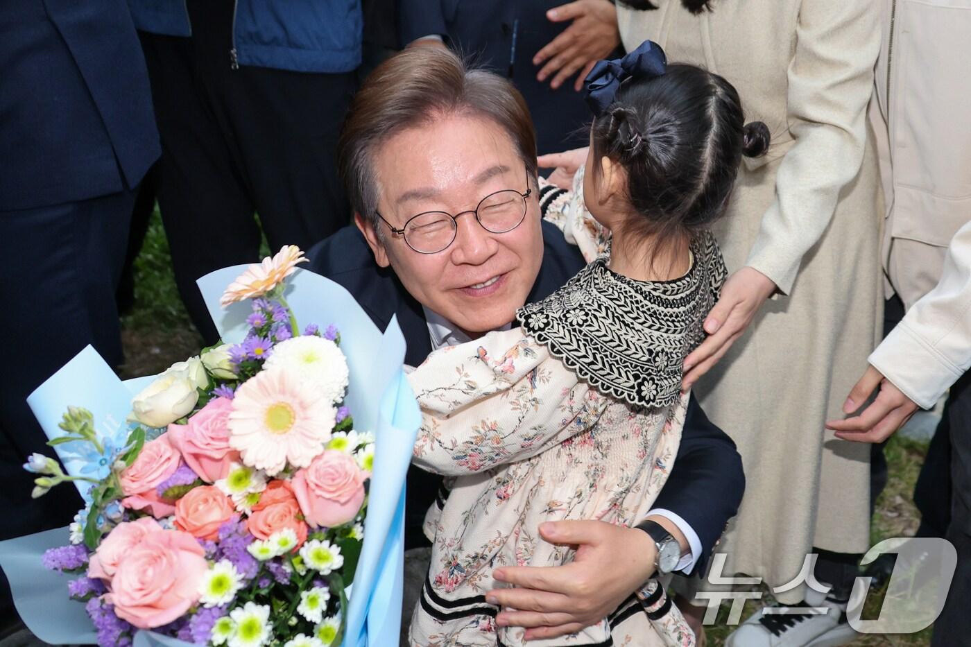 이재명 더불어민주당 대통령 후보가 2차 골목골목 경청투어에 나선 5일 오후 충북 진천군의 혁신도시 상가를 찾아 한 어린이에게 꽃다발을 선물받은 뒤 포옹하고 있다. 2025.5.5/뉴스1 ⓒ News1 안은나 기자