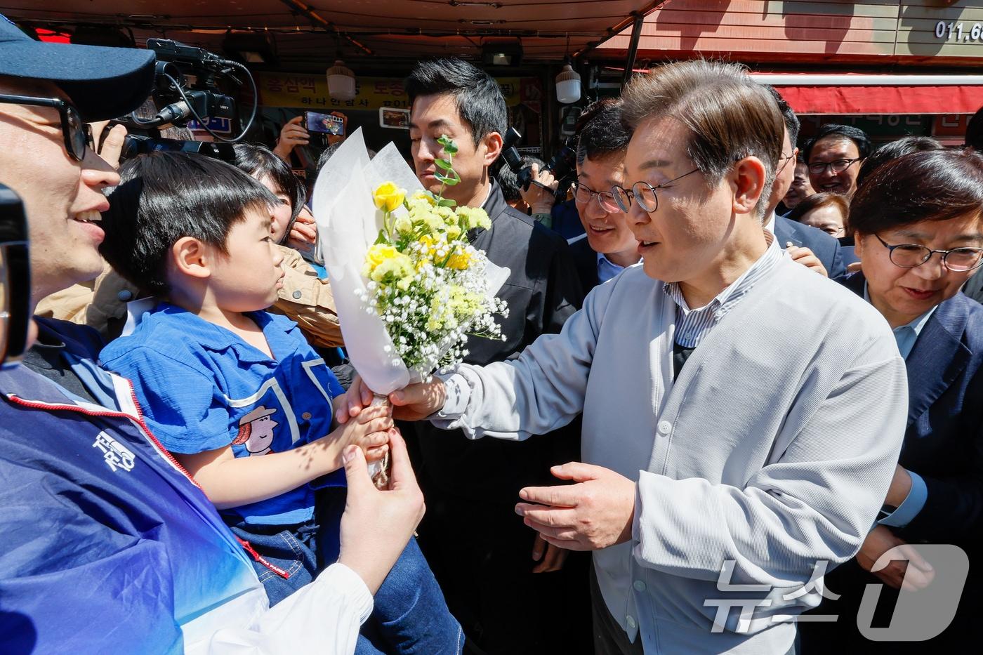 본문 이미지 - 이재명 더불어민주당 대통령 후보가 2차 골목골목 경청투어 마지막 날인 7일 오전 전북 진안군 진무로를 찾아 어린이에게 꽃다발을 선물받고 있다. 2025.5.7/뉴스1 ⓒ News1 안은나 기자