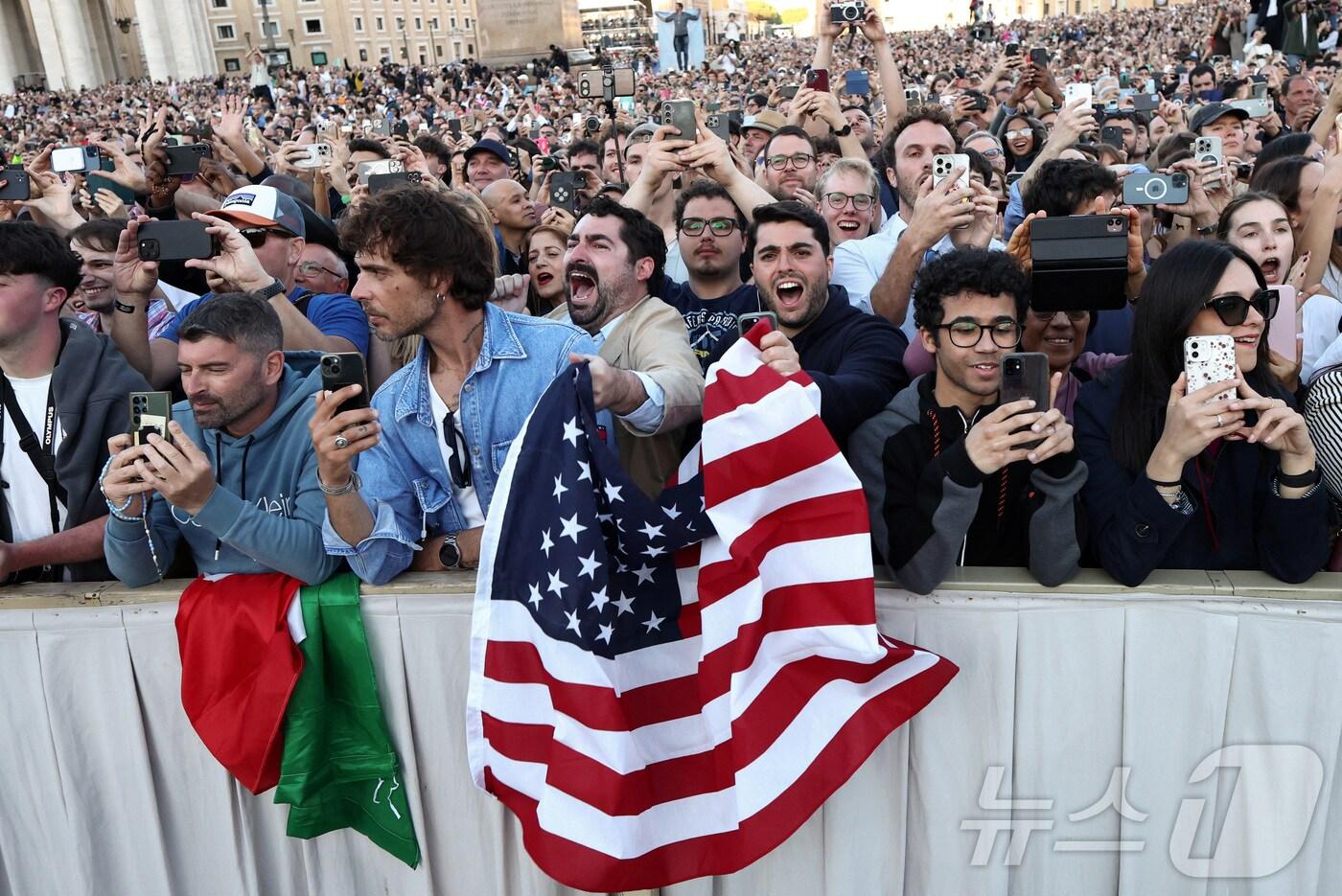 8일(현지시간) 바티칸 시스티나 성당 굴뚝에서 콘클라베가 열린지 이틀 만에 흰 연기가 피어올라 새 교황이 선출됐음을 알리자 성조기를 든 가톨릭 신자들이 기뻐하고 있다 ⓒ 로이터=뉴스1