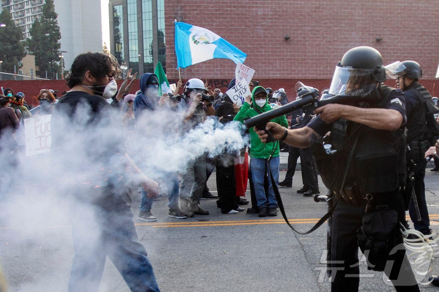 2025년 6월 9일 로스앤젤레스에서 연방 이민 단속 작전 이후 시위 도중 진압 장비를 착용한 경찰이 시위대를 향해 비살상 무기를 발사하고 있다. ⓒ AFP=뉴스1 ⓒ News1 신기림 기자