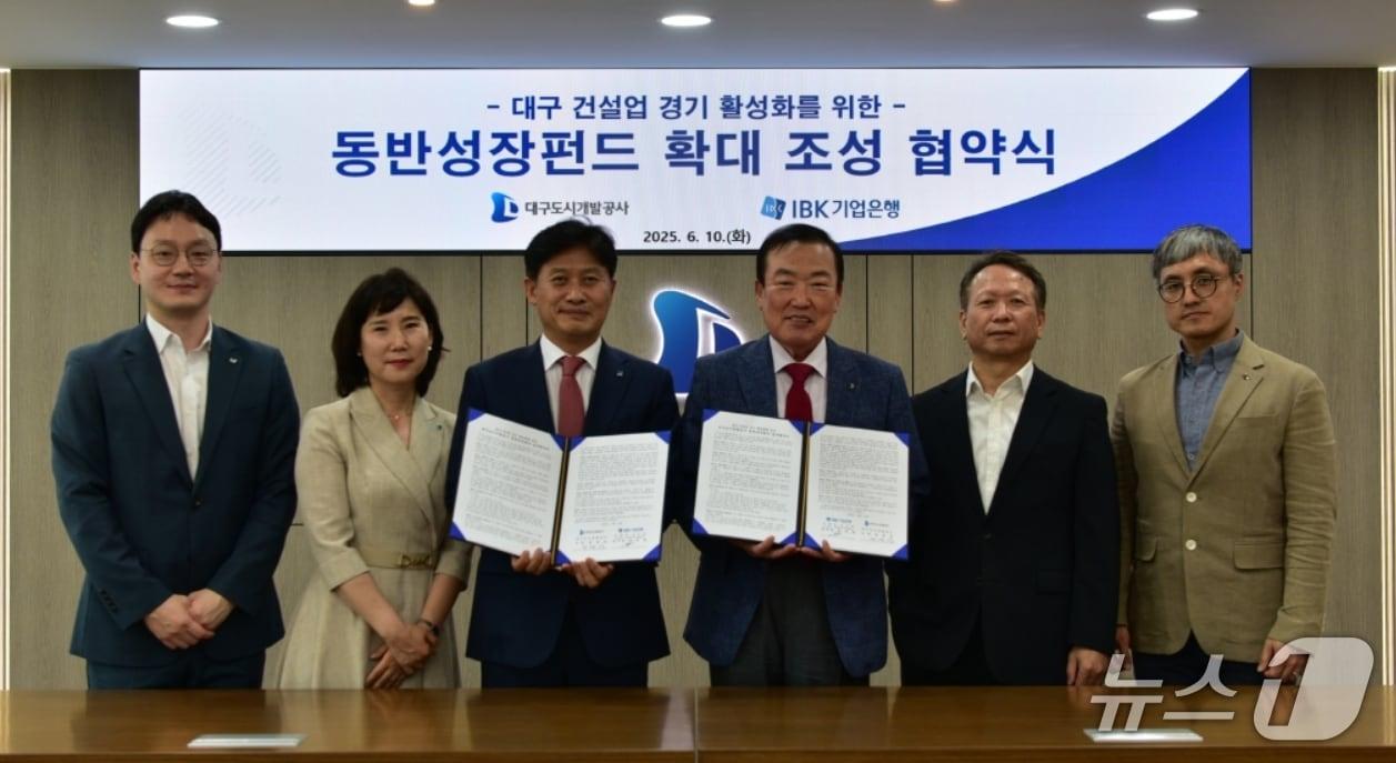 본문 이미지 - 정명섭 대구도시개발공사 사장(오른쪽 세번째)과 이대홍 기업은행 대구경북동부지역본부장(왼쪽 세번째)이 대구 건설업 경기 활성화를 위한 '동반성장펀드 확대 조성' 협약을 체결한 후 협약서를 펼쳐 보이고 있다.(대구도시개발공사 제공. 재판매 및 DB 금지)