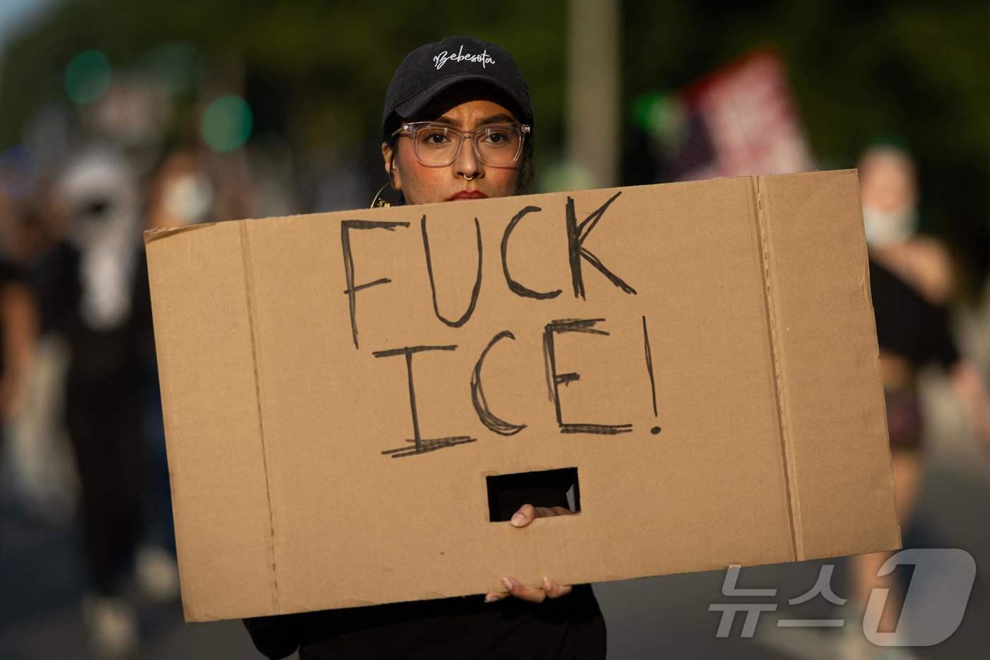 2025년 6월 10일 일리노이주 시카고에서 이민자 권리를 옹호하는 시위자가 거리행진에 참여하며 &#39;엿먹어라, ICE&#40;이민세관단속국&#41;&#39;라고 적힌 팻말을 들고 있다. ⓒ AFP=뉴스1 