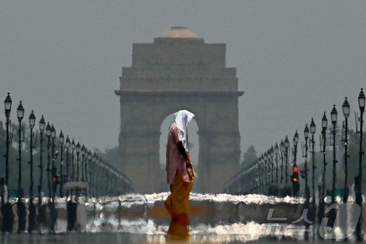 한 인도 여성이 12일(현지시간) 더위에 지친 채로 인도 뉴델리 전쟁기념문(the India Gate) 앞에서 서 있다. 2025.06.12. ⓒ AFP=뉴스1 ⓒ News1 권영미 기자
