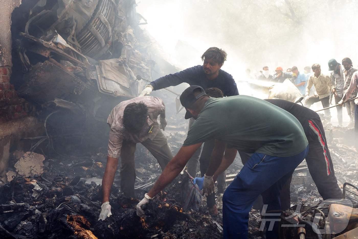인도의 구조대원들이 12일 아마다바드 공항 근처 주거 지역에 떨어진 에어인디아 잔해에서 사고를 수습하고 있다. 2025.06.12. ⓒ AFP=뉴스1