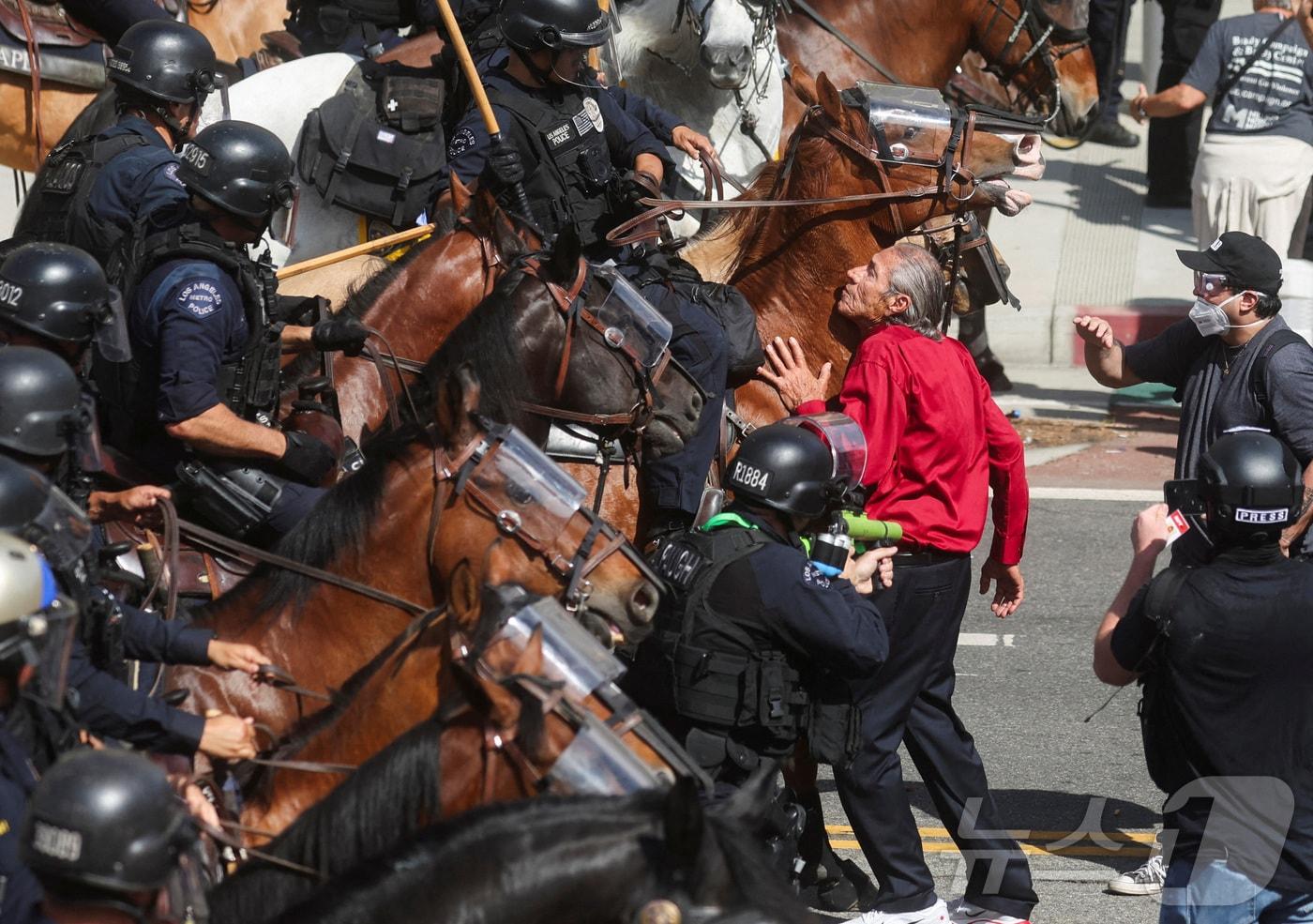 지난 달 14일(현지시간) 미국 캘리포니아주 로스앤젤레스(LA)에서 도널드 트럼프 미국 대통령의 정책과 연방 이민 단속에 반대하는 '노 킹스'(No Kings) 시위에서 한 시위 참여자가 기마 경찰을 막는 모습. ⓒ 로이터=뉴스1 ⓒ News1 류정민 특파원