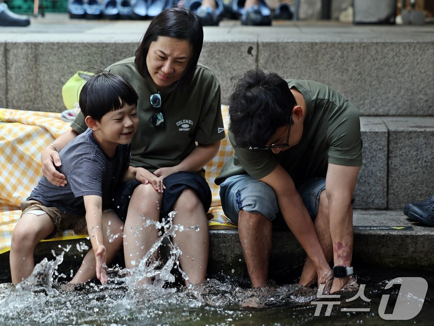 본문 이미지 - 서울 최고기온이 29도까지 오르는 등 초여름 날씨를 보인 17일 오후 청계천을 찾은 시민들이 물 속에 발을 담그며 더위를 식히고 있다. 2025.6.17/뉴스1 ⓒ News1 황기선 기자
