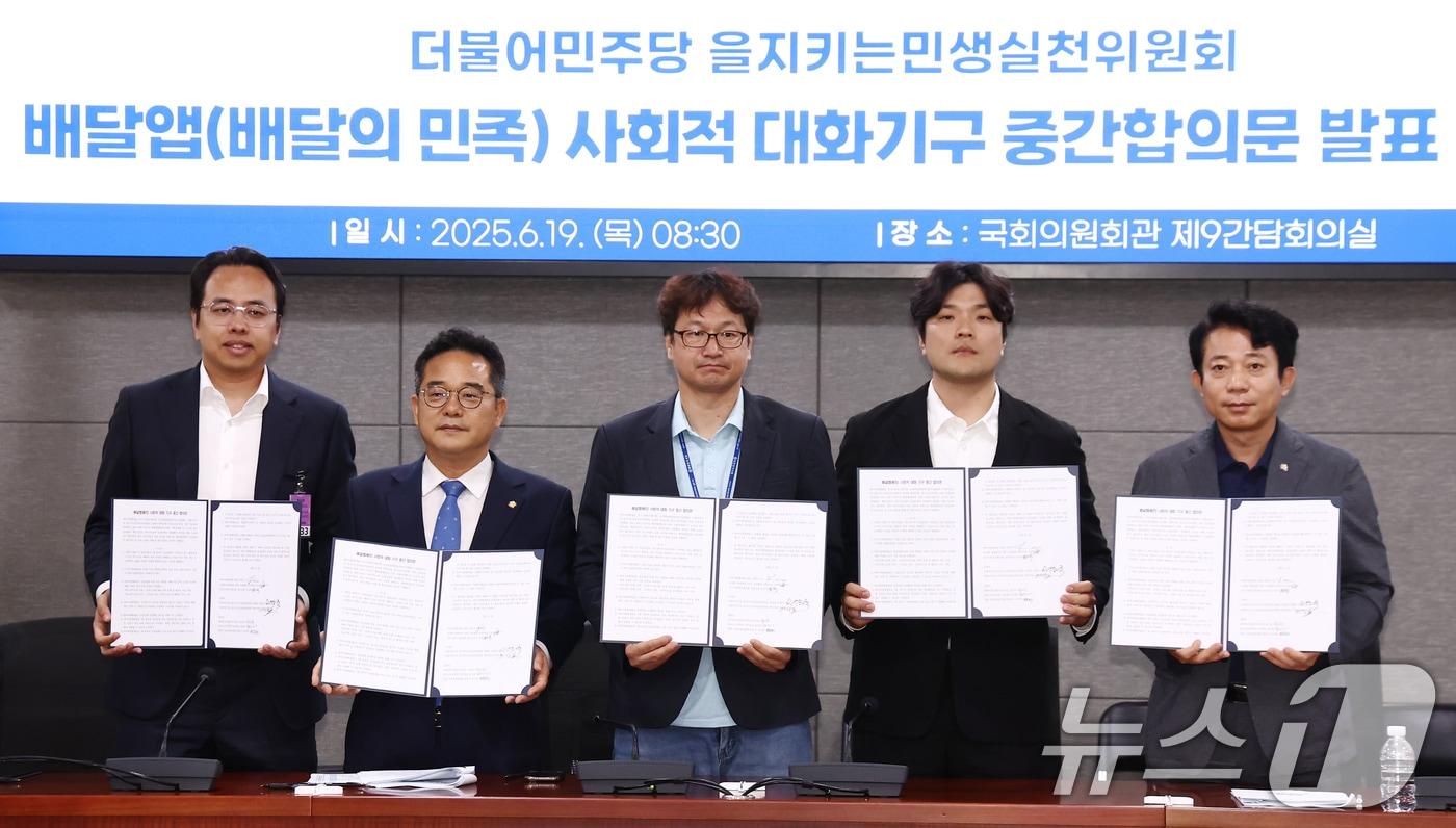 더불어민주당 을지로위원회 민병덕 위원장과 김범석 우아한형제들 대표, 김진우 전국가맹점주협의회 의장 등 참석자들이 19일 오전 서울 여의도 국회에서 배달앱&#40;배달의민족&#41; 사회적대화기구 중간합의문 발표 브리핑에서 중간합의문에 서명한 뒤 기념촬영을 하고 있다. 2025.6.19/뉴스1 ⓒ News1 김민지 기자