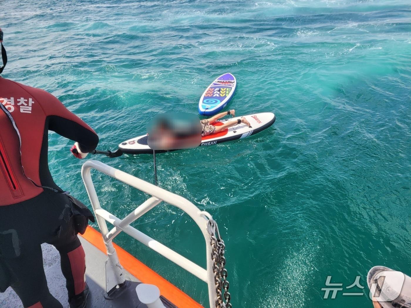 본문 이미지 - 제주해경이 패들보드로 관광객을 구하려다 표류한 레저업체 직원을 구조하고 있다./뉴스1 