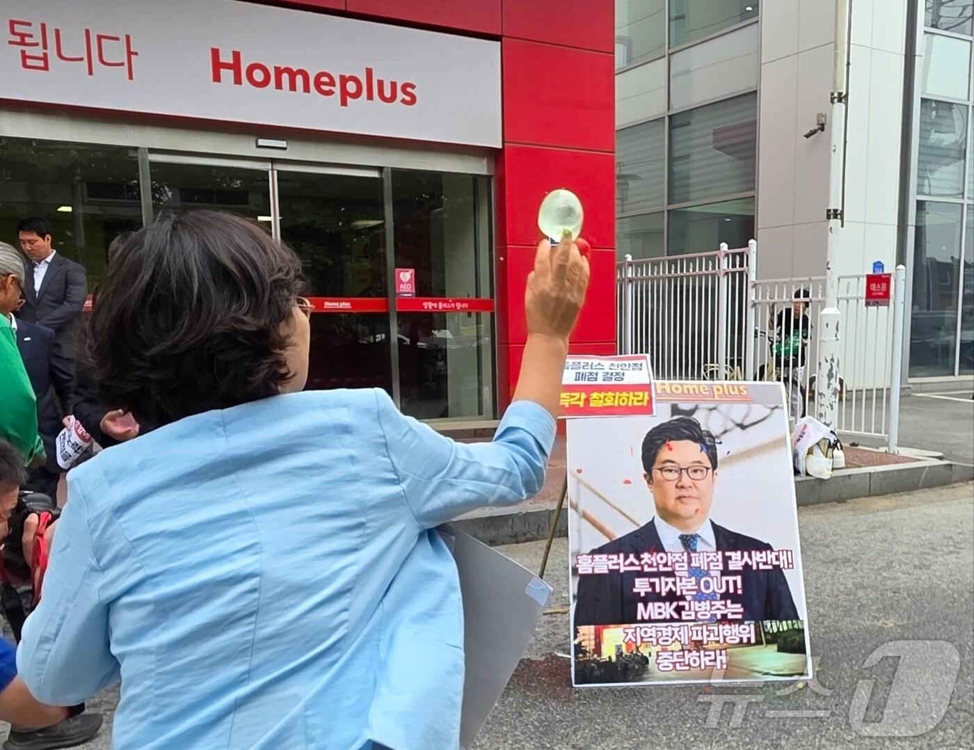 본문 이미지 - 마트 노동자들이 2일 천안시 동남구 홈플러스 천안점 앞에서 열린 폐점 반대 기자회견에서 김병주 MBK파트너스 회장을 규탄하며 얼굴 사진에 물풍선을 던지고 있다. 2025.6.2/뉴스1 ⓒ News1 이시우 기자
