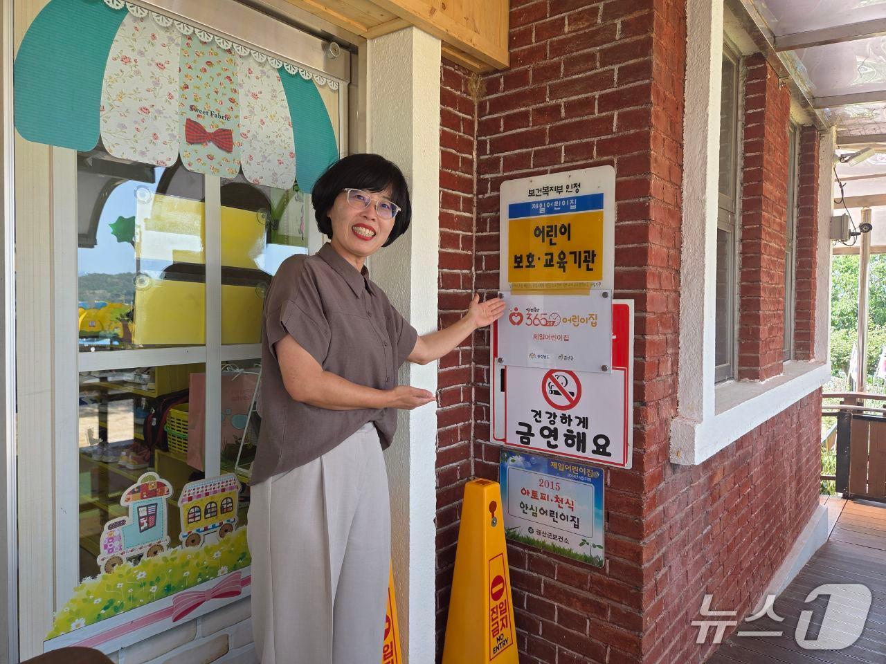 본문 이미지 - 곽영주 제일어린이집 원장이 365x24 어린이집 현판 앞에서 기념사진을 찍고 있다. (금산군 제공.재판매 및 DB 금지)/뉴스1