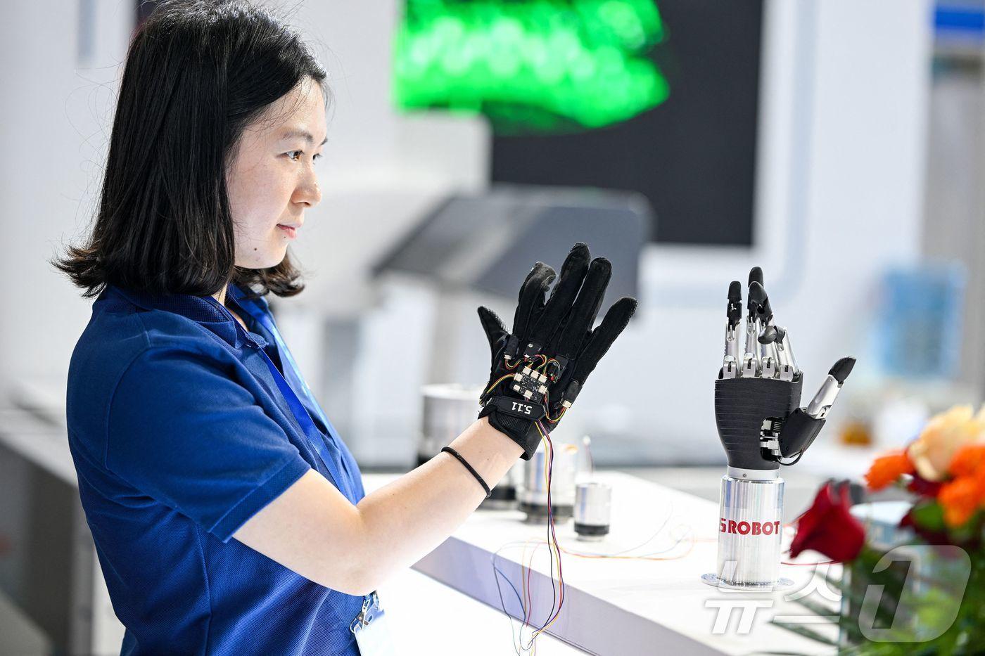 6월 20일 중국 동부 장쑤성 난징에서 열린 2025 세계 반도체 컨퍼런스- 엑스포에서 한 직원이 촉각 장갑을 사용하여 생체공학 팔을 원격으로 제어하고 있다. &lt;자료 사진&gt; 2025.6.20 ⓒ AFP=뉴스1 ⓒ News1 신기림 기자
