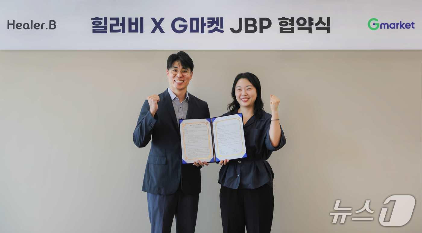 조성훈 힐러비 브랜드커머스 그룹장&#40;왼쪽&#41;과 유보연 G마켓 뷰티 팀장이 업무 제휴 체결 후 기념 촬영을 하고 있다.&#40;코웨이 제공&#41;