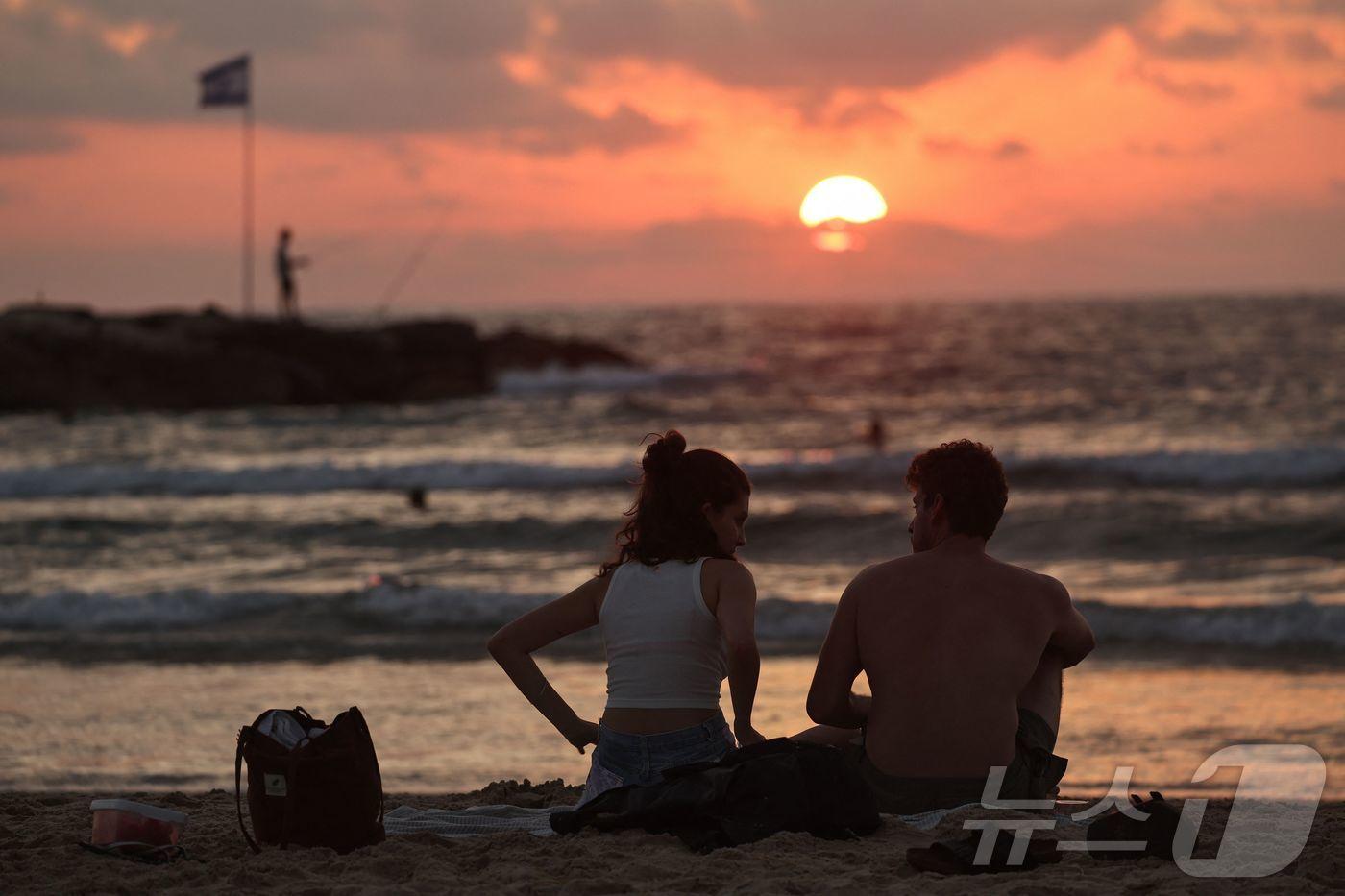 24일(현지시간) 이스라엘과 이란 간 휴전이 시작된 가운데 이스라엘 텔아비브 해변에 커플이 앉아 있다. 25.06.24 ⓒ AFP=뉴스1 ⓒ