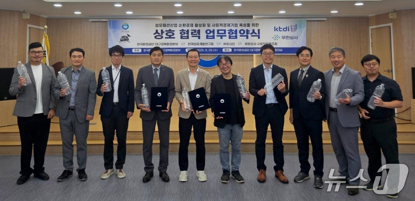 한국섬유개발연구원과 한국환경공단 대구경북환경본부, ㈜우시산, 무한상사 사회적협동조합 직원들이 산업 현장의 폐 페트병을 안전 소재로 개발 및 보급하기 위한 업무협약을 체결한 뒤 폐 페트병을 들고 기념촬영을 하고 있다.(섬유개발연구원 제공. 재판매 및 DB 금지)