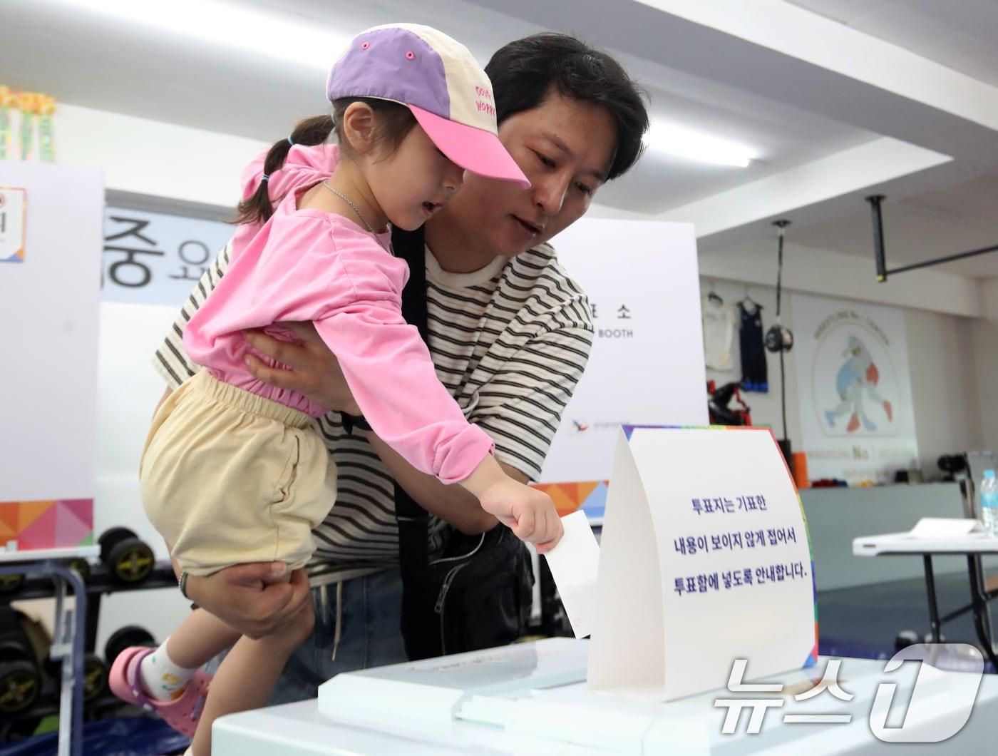 본문 이미지 - 제21대 대통령 선거일인 3일 부산 수영구 레슬링넘버원 멀티짐에 마련된 남천제2동 제3투표소에서 유권자가 아이와 함께 투표를 하고 있다. 2025.6.3/뉴스1 ⓒ News1 윤일지 기자