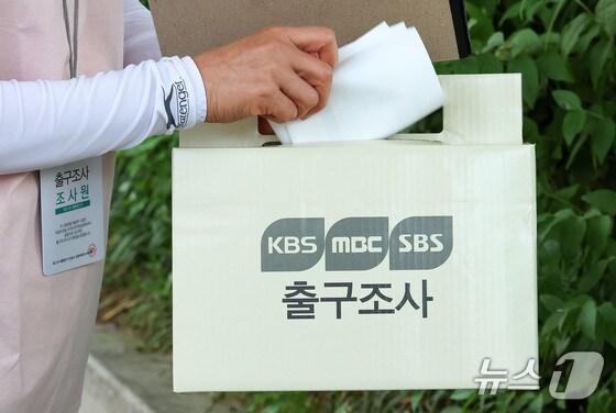 본문 이미지 - 21대 대통령 선거일인 3일 서울시내 한 투표소 앞에서 방송3사 공동 출구조사 조사원이 조사결과지를 함에 넣고 있다. 2025.6.3/뉴스1 ⓒ News1 박세연 기자 