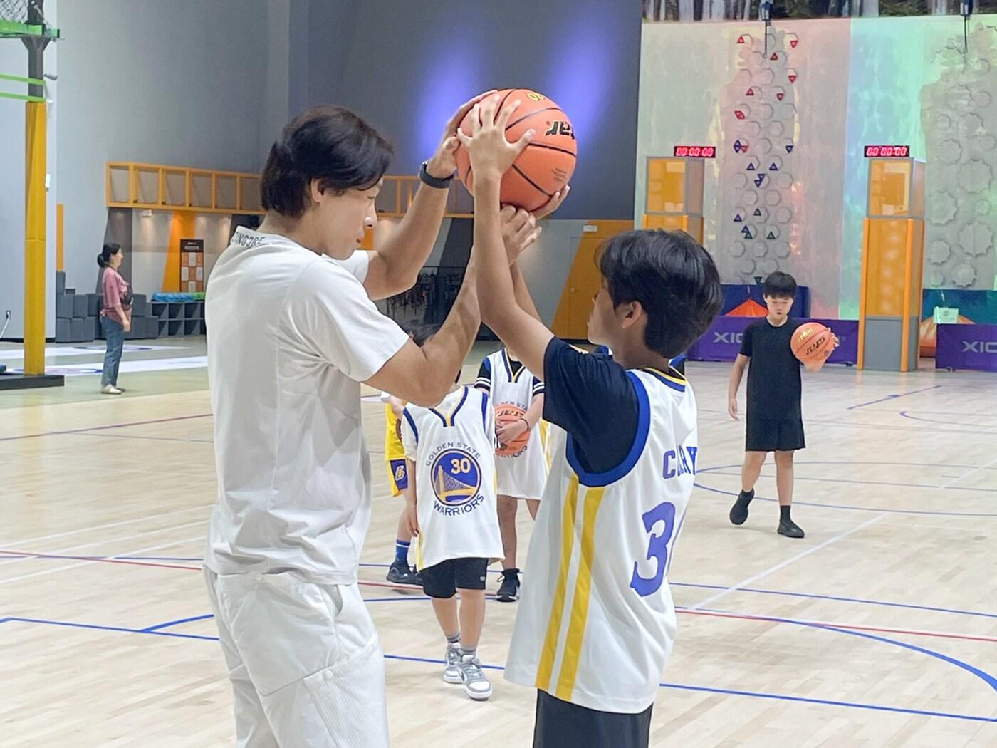 본문 이미지 - 'KSPO 스포츠 가치교육 캠프' 참가자들이 지도자의 도움을 받으며 농구 수업을 받고 있다. (체육공단 제공)